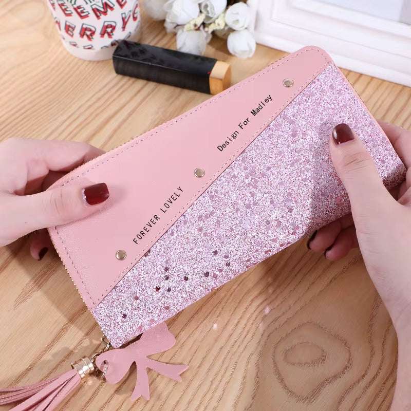 Pink fashion womens PU leather wallet with glitter and tassel charm on wooden table