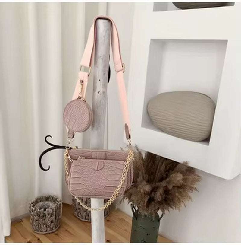 Vintage crocodile pattern women shoulder bag with chain and wide strap in pink tone hanging on wooden stand