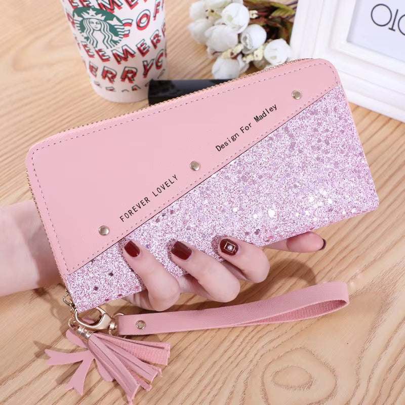 Fashion womens PU leather pink glitter wallet with wrist strap and tassel on wooden table