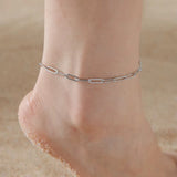 Silver knot pendant anklet on sandy foot in close-up view