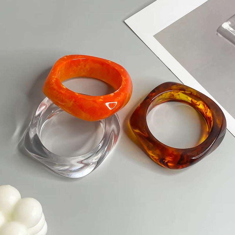 Vintage colorful irregular acrylic resin bracelets in orange and brown transparent colors on a gray surface