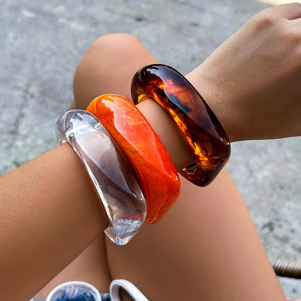Vintage colorful irregular acrylic resin bracelets in transparent brown, orange and clear colors worn on wrist
