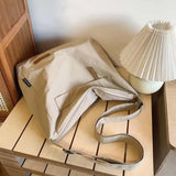 Japanese unisex beige shoulder bag on wooden table next to lamp