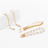Set of imitation pearl chain bracelets with gold-colored alloy and iron links on white background