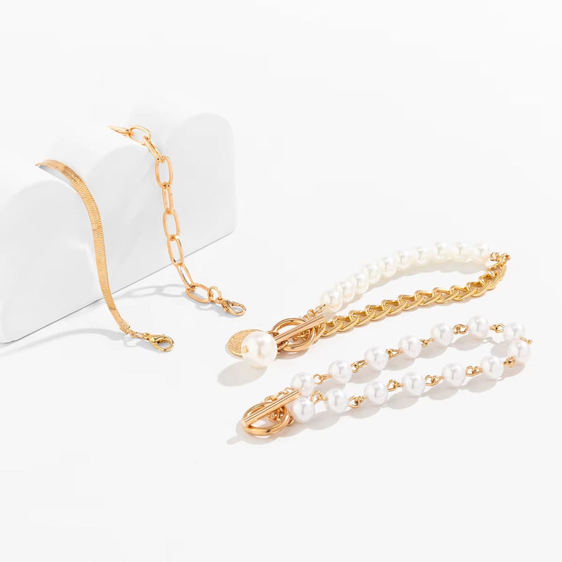 Set of imitation pearl chain bracelets with gold-colored alloy and iron links on white background