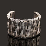 Silver woven punk style cuff bangle bracelet with intricate braided design on black background