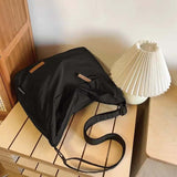 Black Japanese unisex shoulder bag on wooden table next to white pleated lamp
