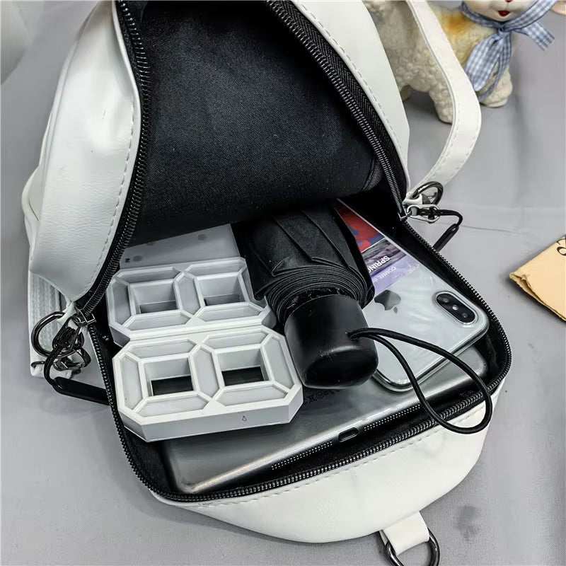 white handbag open showing black umbrella, smartphone, and white geometric organizer inside on gray surface