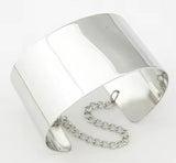 Shiny metallic silver chained cuff bracelet with smooth wide band and attached chain clasp