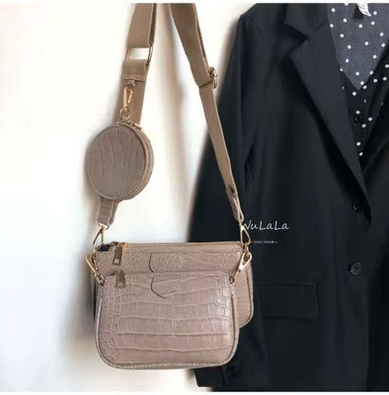 Vintage crocodile pattern women's shoulder bag with wide strap and small round pouch in beige color hanging on black outfit
