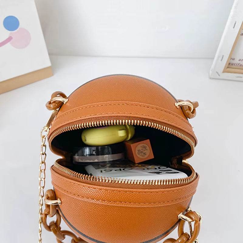 Brown basketball-shaped ball purse for teenagers with gold chain zipper open showing cosmetic items inside