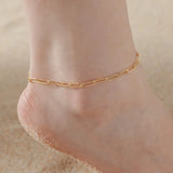 Gold knot pendant anklet chain on sandy foot close-up