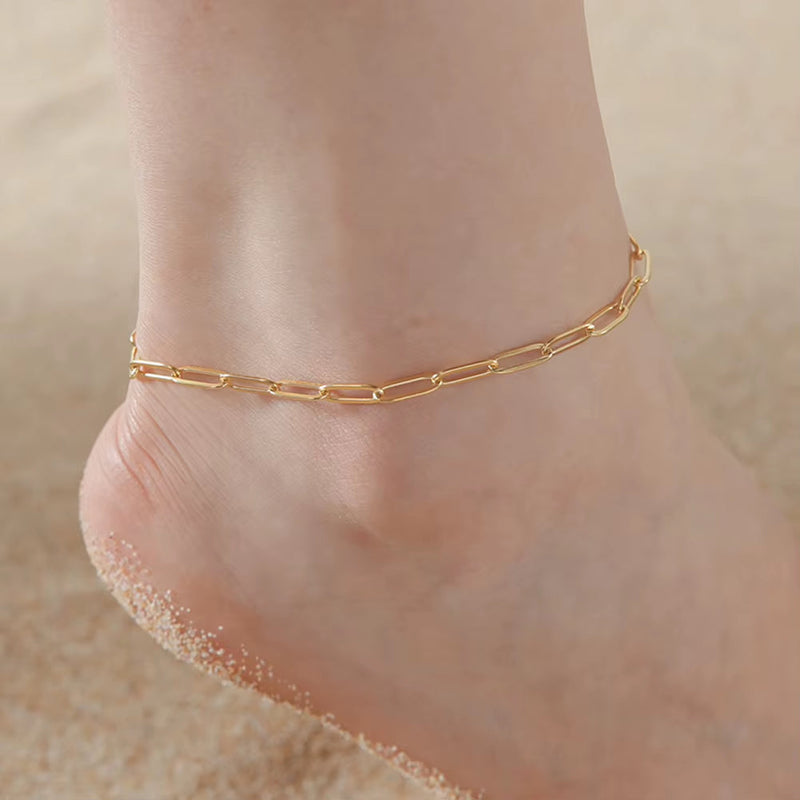 Gold knot pendant anklet chain on sandy foot close-up