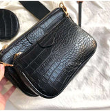 Black vintage crocodile pattern women shoulder bag with gold hardware and wide strap on light fabric background