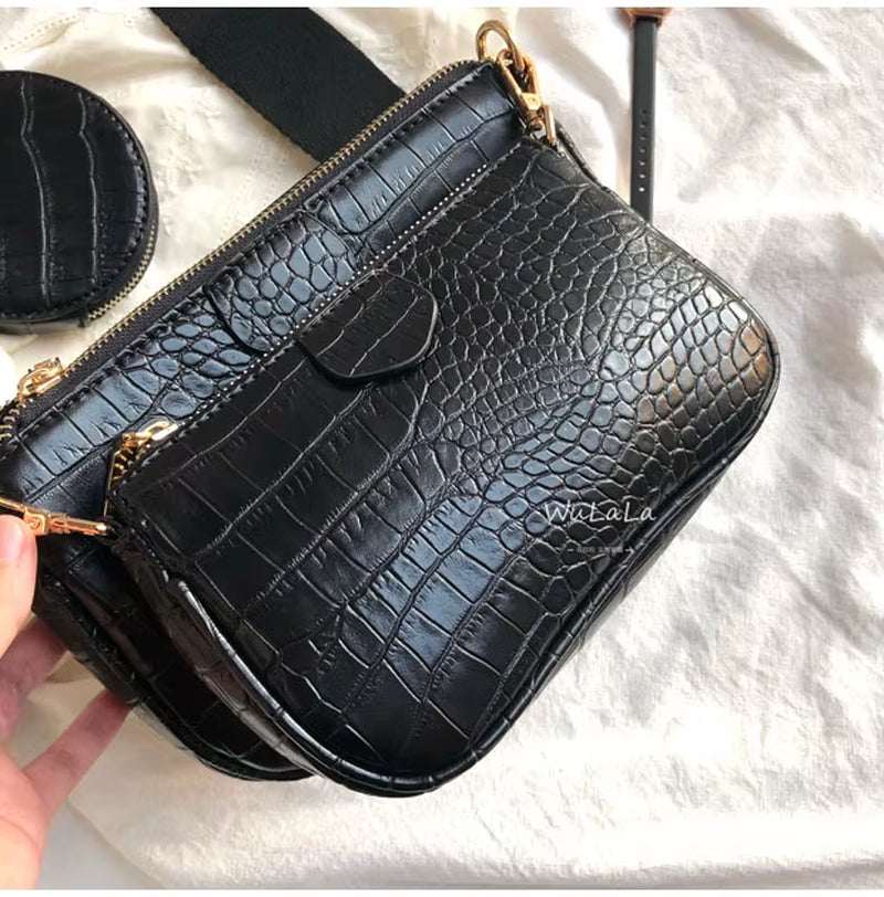 Black vintage crocodile pattern women shoulder bag with gold hardware and wide strap on light fabric background
