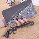 Fashion women's PU leather glitter wristlet wallet with tassel and bow charm on wooden table