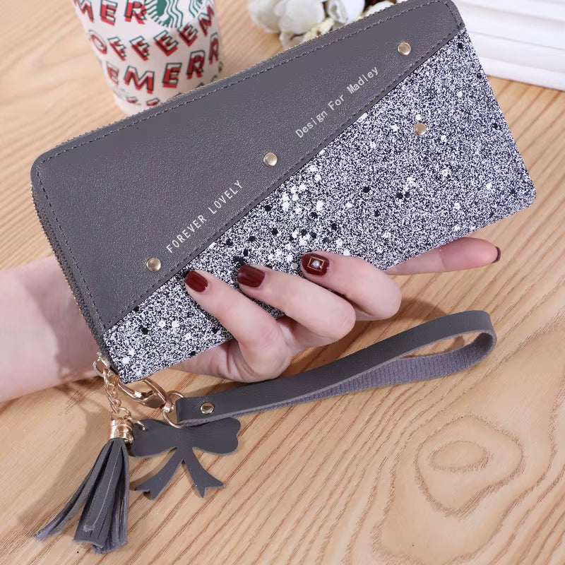 Fashion women's PU leather glitter wristlet wallet with tassel and bow charm on wooden table