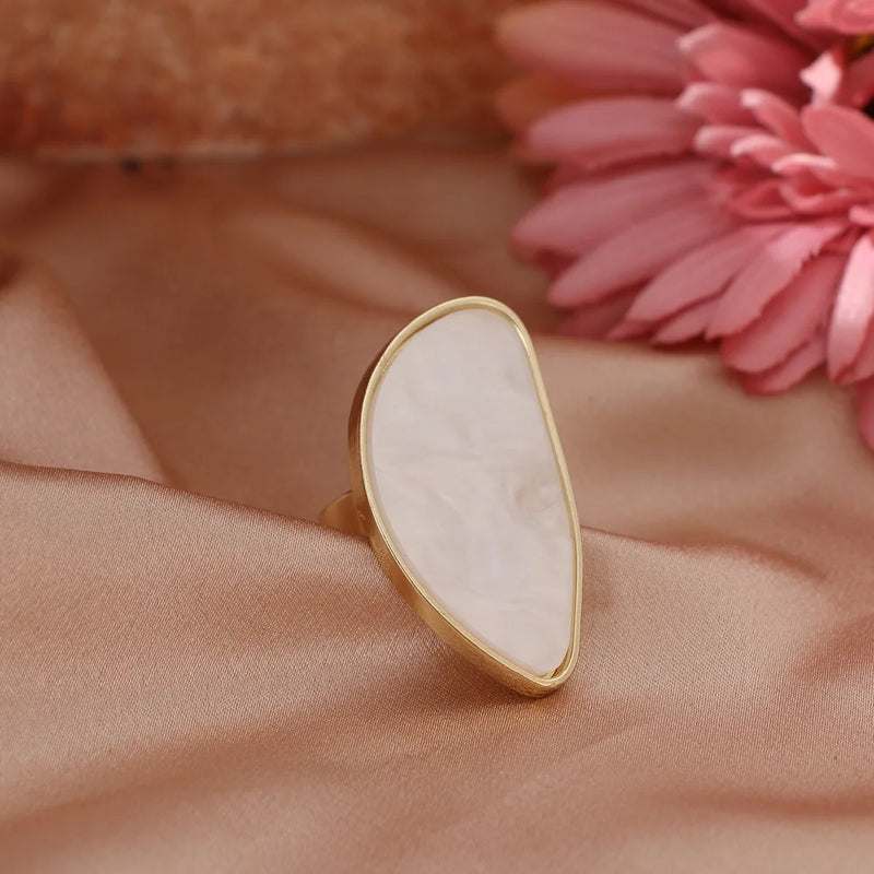Elegant fashion woman ring with white stone and gold trim on satin background