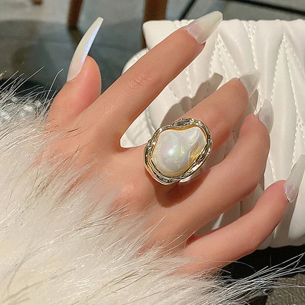 Fashion woman ring with large pearl detail on hand with white nails and fur sleeve