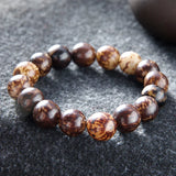 Nature Bodhi 18 Style Beads Bracelet made of natural Rudraksha beads with earthy brown tones on a dark fabric background