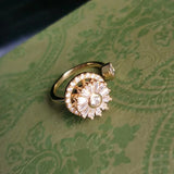 Elegant gold fidget spinner ring with gemstone detailing on green patterned background