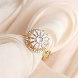 Elegant gold fidget spinner ring with sparkling clear crystals on beige fabric background