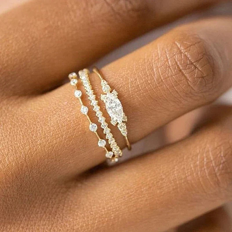 Close-up of hand wearing three delicate stackable gold rings with cubic zirconia stones