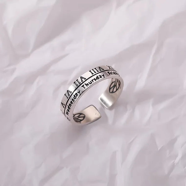 Silver fidget spinner ring with calendar and Roman numerals design on crumpled white background