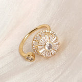 Gold fidget spinner ring with clear crystals on beige fabric background