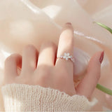 Close-up of hand wearing a pink romantic flower ring with a white flower design on a soft background
