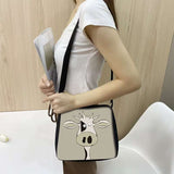 Cow print small shoulder bag with cartoon cow design worn by woman