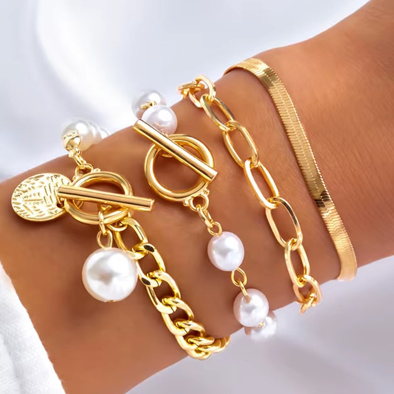 Close-up of wrist wearing gold imitation pearl chain bracelets and bangles set