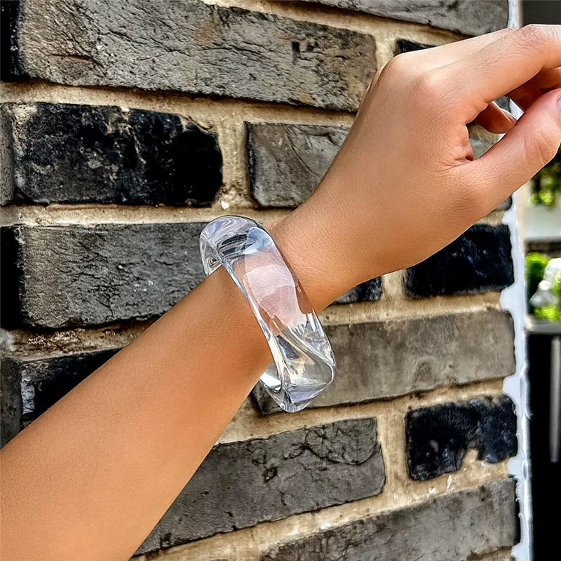 Vintage colorful irregular clear acrylic resin bracelet on wrist against brick wall background