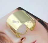 Metallic gold wide cuff bracelet with chain detail on display