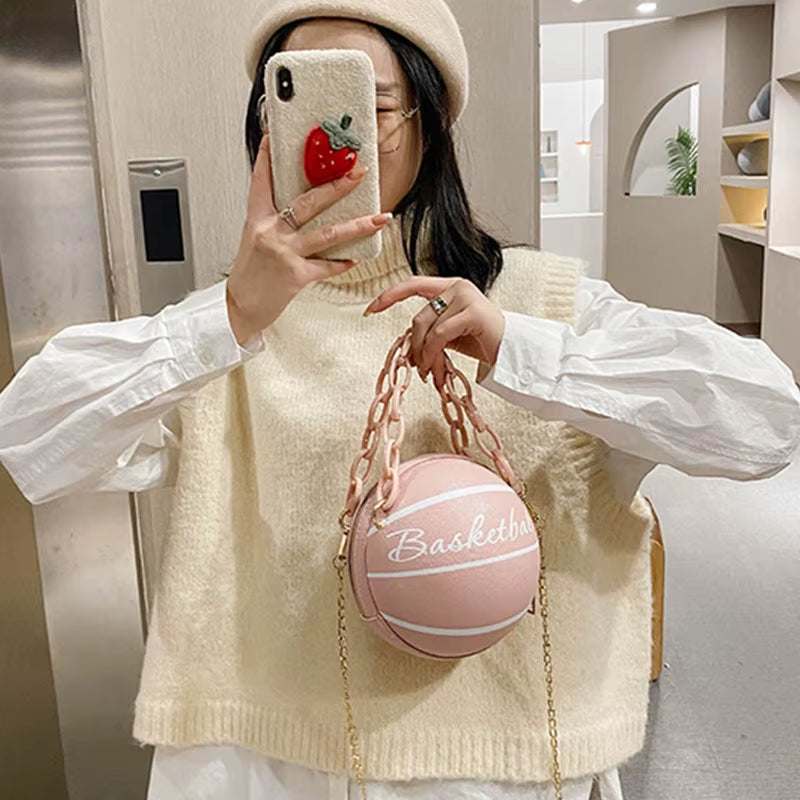 Teenager holding pink basketball-shaped ball purse with chain strap in stylish outfit