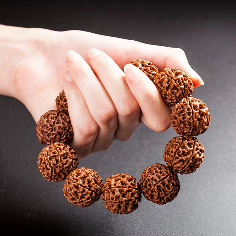 Hand holding fashion Rudraksha beads bracelet against dark background