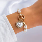 Imitation pearl chain bracelet with heart charm and gold accents on wrist