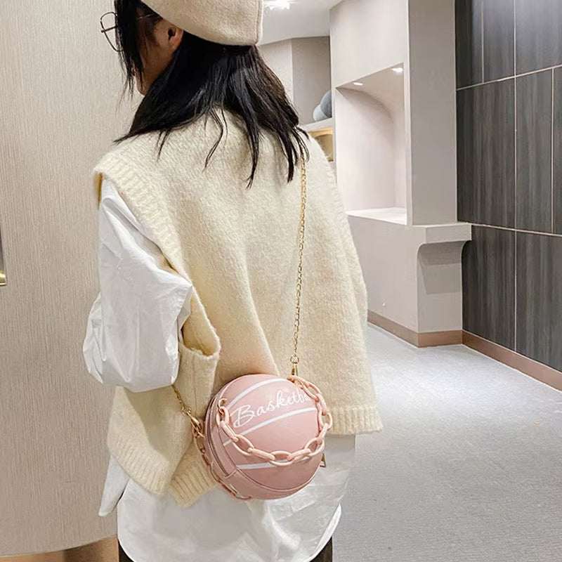 Teen girl wearing a cream knit vest and beret with a pink basketball-shaped PU leather ball purse crossbody bag with acrylic chain strap.